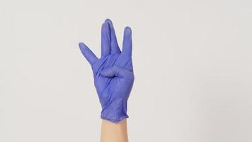le signe de la main de la côte ouest hip-hop et la main portent un gant en latex violet ou violet sur fond blanc. photo