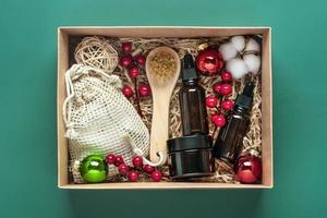 ensemble pour boîte de soins bouteilles d'huile et de crème cosmétiques écologiques, brosse pour le lavage, tampons de coton sur fond vert cadeau pour petite amie, mère pour célébrer le concept de noël vue de dessus à plat photo