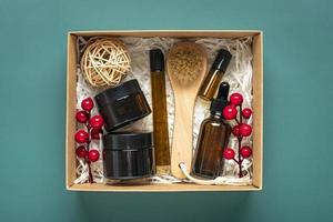 ensemble pour boîte de soins bouteilles d'huile et de crème cosmétiques écologiques, brosse pour le lavage, tampons de coton sur fond vert cadeau pour petite amie, mère pour célébrer le concept de noël vue de dessus à plat photo