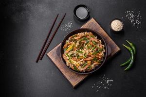 plat savoureux de cuisine asiatique avec nouilles de riz, poulet, asperges, poivre, graines de sésame et sauce soja