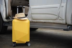 valise avec chapeau et voiture, préparation ou vérification de votre voiture avant un concept de road trips. photo