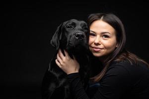 une fille tient un chien labrador retriever dans ses bras. photo