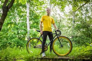 un jeune homme s'est arrêté pour se reposer avec son vélo dans un parc public. photo