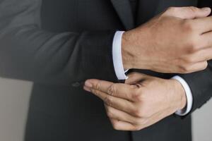 pose de préparation en gros plan d'un homme fixant et d'un homme tenant des boutons sur les manches du costume et de la chemise blanche. photo