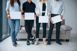 vue de face d'un jeune groupe d'amis tenant des papiers vides dans les mains photo