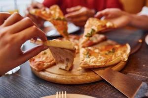 vue rapprochée des personnes qui prennent et mangent de la pizza à l'intérieur ensemble photo