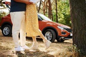 jambes de couple qui s'embrassent à l'extérieur dans la forêt contre un véhicule moderne photo