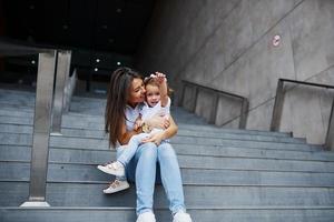 jolie jeune mère et sa petite fille se promènent dans la ville photo