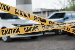 véhicules noirs et blancs. ruban de mise en garde jaune près du parking pendant la journée. scène de crime photo