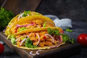 tacos mexicains avec tortilla de maïs. tortilla avec viande de poulet, maïs, laitue et oignon photo