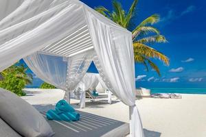 incroyable fond de vacances d'été. paysage de luxe de plage avec auvent de plage blanche et chaises longues. île paradisiaque relaxante, paysage tropical luxueux. scène de rêve, plage de sérénité, verrière de salon photo