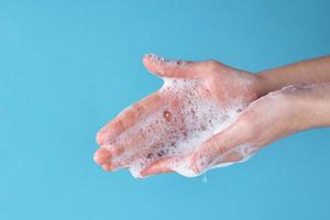 femme se laver les mains avec du savon sur un fond bleu photo