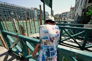 garçon touriste porter panama stand et attendre dans le quai de la gondole en bois, venise, italie. photo