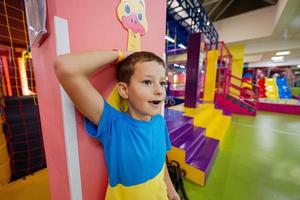 le garçon mesure sa taille avec une règle à l'aire de jeux intérieure du centre de jeux. photo