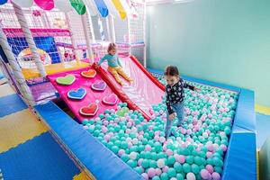 soeurs heureuses jouant à l'aire de jeux intérieure du centre de jeux, boules de couleur dans la piscine à balles. photo