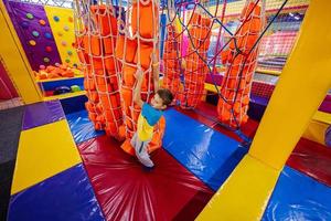 enfants heureux jouant à l'aire de jeux intérieure du centre de jeux, garçon grimpe les cordes. photo