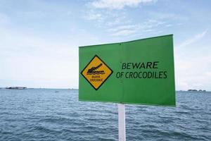Panneau d'avertissement de danger de crocodile qui vit dans la mer photo