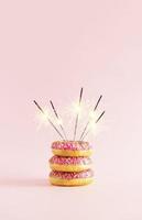 gâteau beignet avec cierges magiques sur fond rose. composition minimale. idée créative de fête.