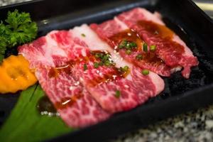 tranches de bœuf japonais crues de qualité supérieure saupoudrées de graines de sésame blanches et d'oignons de printemps tranchés