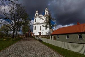 une église catholique blanche un jour d'été avec des nuages sombres en arrière-plan photo