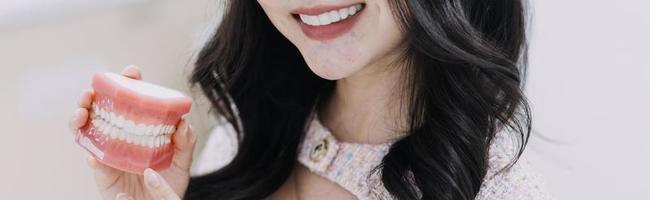 concept de stomatologie, portrait partiel d'une fille avec de fortes dents blanches regardant la caméra et souriant, les doigts près du visage. gros plan sur une jeune femme chez le dentiste, en studio, à l'intérieur photo