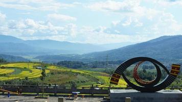 la vue sur le champ de riz jaune de récolte situé dans la vallée parmi les montagnes avec le ciel nuageux en arrière-plan photo