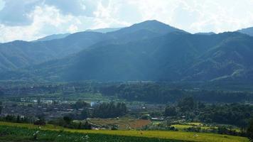 la vue sur le champ de riz jaune de récolte situé dans la vallée parmi les montagnes avec le ciel nuageux en arrière-plan photo