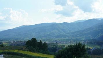 la vue sur le champ de riz jaune de récolte situé dans la vallée parmi les montagnes avec le ciel nuageux en arrière-plan photo