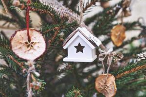 maison de jouet vintage et pomme séchée sur l'arbre de noël. ornements de noël naturels pour sapin de noël, zéro déchet photo