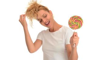 femme blonde léchant des bonbons sucrés. modèle féminin mangeant une délicieuse sucette de confiserie avec une expression surprise. photo