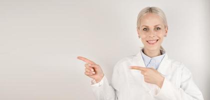 jeune femme médecin heureuse pointant vers l'espace vide.bannière médicale avec place pour le texte photo