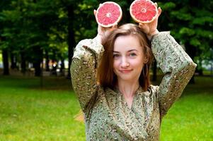 portrait de fille d'été aux cheveux rouges. femme tenant un pamplemousse s'amusant. photo