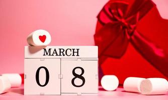 bannière créative de la journée de la femme avec des cadeaux en forme de coeur, des guimauves et un calendrier avec la date du 8 mars photo