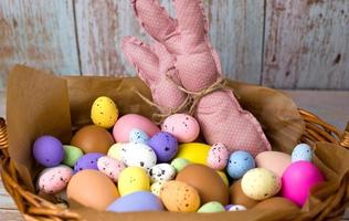 gros plan de lapins jouets roses dans le panier rempli d'œufs colorés. bannière de joyeuses pâques photo