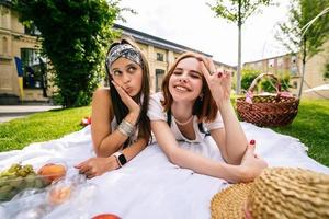 deux femmes pique-niquent ensemble, allongées sur la pelouse du parc photo