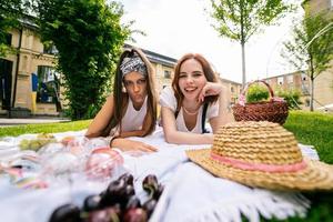 deux femmes pique-niquent ensemble, allongées sur la pelouse du parc photo