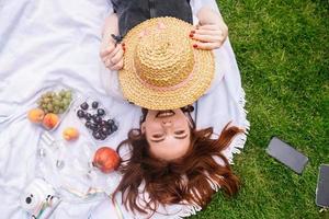 jeune femme couvre le visage avec un chapeau en position allongée sur la pelouse photo