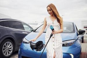 femme sur la station de charge des voitures électriques pendant la journée. véhicule neuf photo
