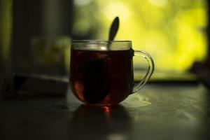 thé en verre. thé le matin. tasse transparente sur la table. petit déjeuner à l'aube. photo