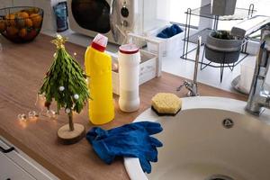 nettoyer la cuisine avant les vacances de noël et du nouvel an. détergent, poudre sèche, éponge, gants sont sur l'évier. décor festif dans la cuisine blanche, intérieur cosy de la maison