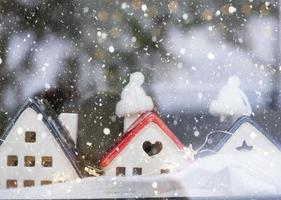 la maison confortable est enveloppée dans un chapeau et une écharpe dans un décor de rebord de fenêtre de tempête de neige. hiver, neige - isolation de la maison, protection contre le froid et les intempéries, système de chauffage des locaux. ambiance festive, noël, nouvel an photo