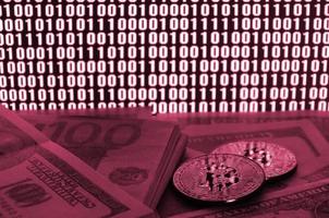 deux bitcoins se trouvent sur une pile de billets d'un dollar sur le fond d'un moniteur représentant un code binaire de zéros brillants et une image d'unités en viva magenta, couleur de l'année 2023 photo