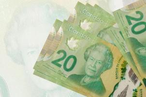 20 billets de dollars canadiens sont empilés sur fond de gros billets de banque semi-transparents. présentation abstraite de la monnaie nationale photo