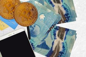 Billets de 5 dollars canadiens et bitcoins dorés avec smartphone et cartes de crédit. concept d'investissement en crypto-monnaie. minage ou commerce de crypto photo