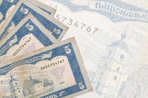 5 billets de hryvnias ukrainiens sont empilés sur fond de gros billets de banque semi-transparents. arrière-plan abstrait des affaires photo