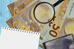 Billets de 50 euros et loupe avec sac à main noir et bloc-notes. concept de fausse monnaie. rechercher les différences dans les détails des billets de banque pour détecter les faux photo