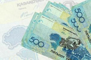 500 billets de tenge kazakhstanais sont empilés sur fond de gros billets semi-transparents. présentation abstraite de la monnaie nationale photo