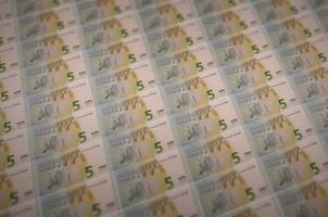 Billets de 5 euros imprimés dans un convoyeur de production d'argent illégal. collage de nombreux faux billets. concept de travail des contrefacteurs photo
