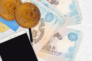 200 billets de hryvnias ukrainiens et bitcoins dorés avec smartphone et cartes de crédit. concept d'investissement en crypto-monnaie. minage ou commerce de crypto photo