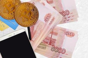 Billets de 5000 roubles russes et bitcoins dorés avec smartphone et cartes de crédit. concept d'investissement en crypto-monnaie. minage ou commerce de crypto photo